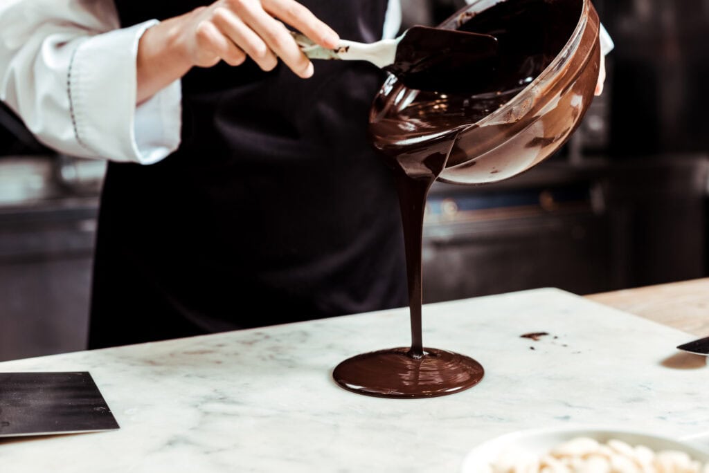 Expert chocolatier drizzling molten chocolate
