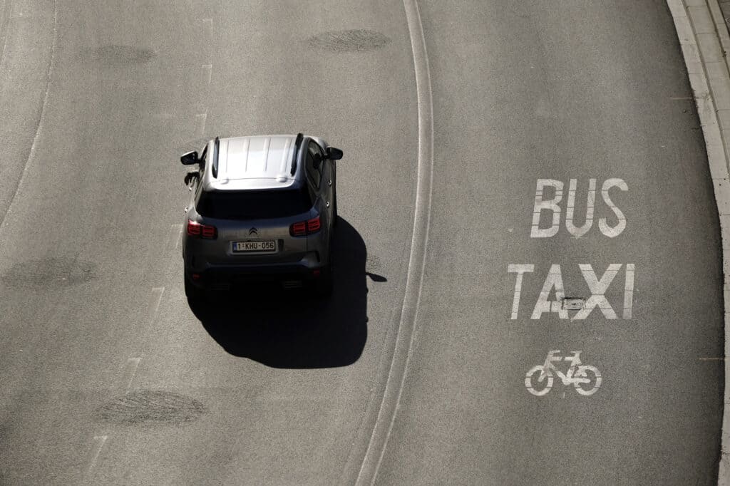 a gray car and a lane for buses and taxis