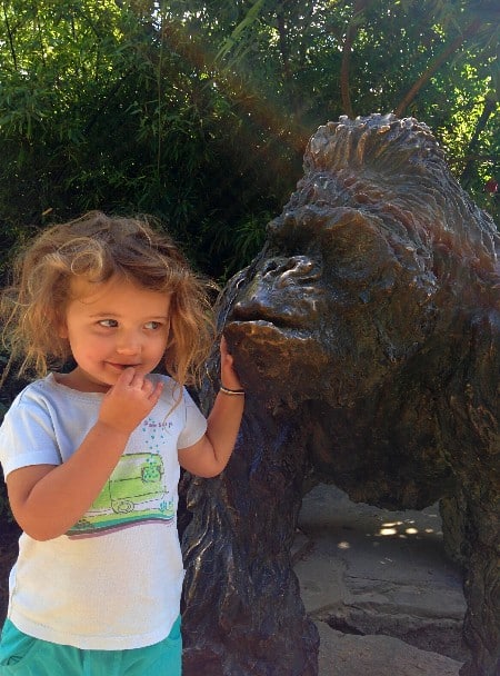 Toddler girl posing beside a gorilla statue