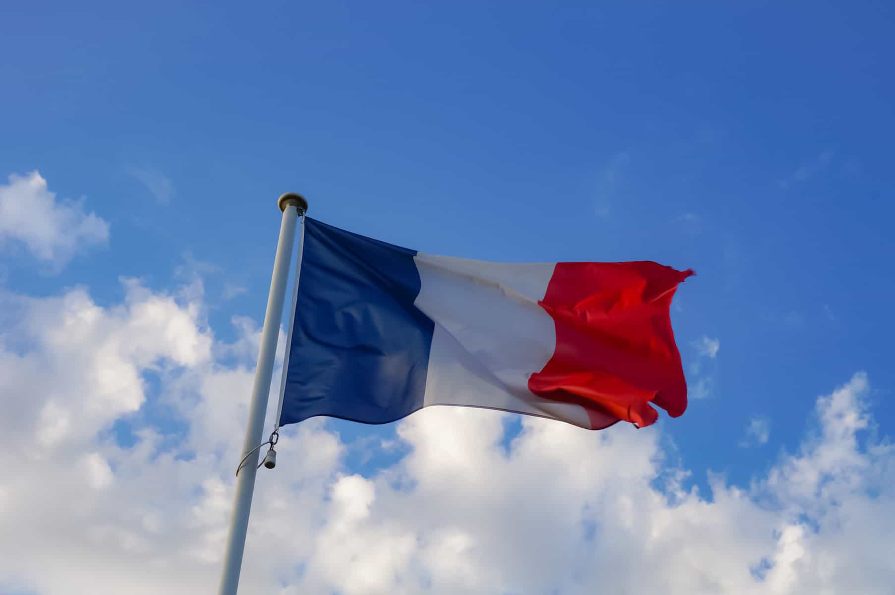 Flag of France against a bright blue sky.