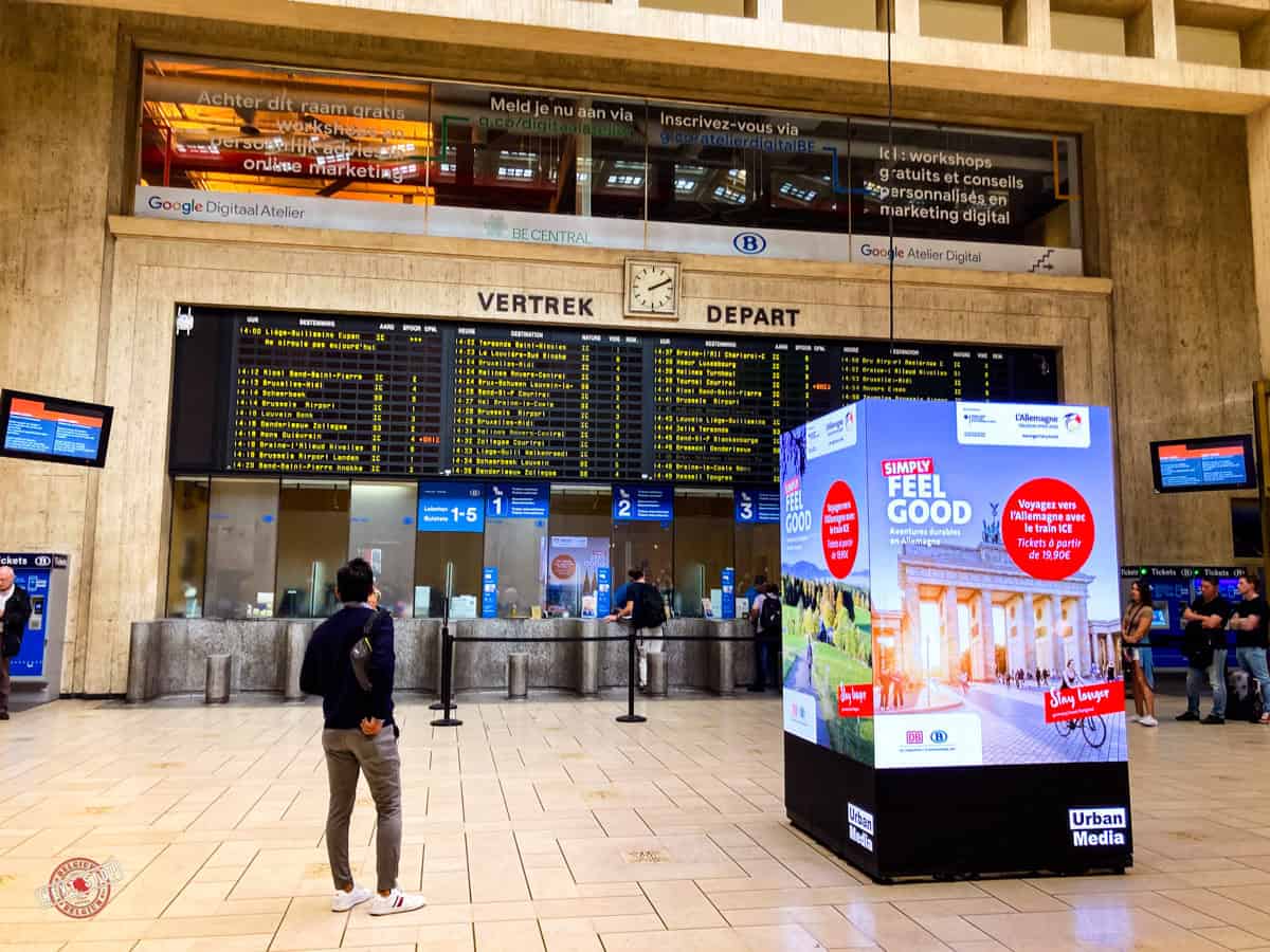 man checking the train schedule and time table at the entry hall of Brussels Central Station