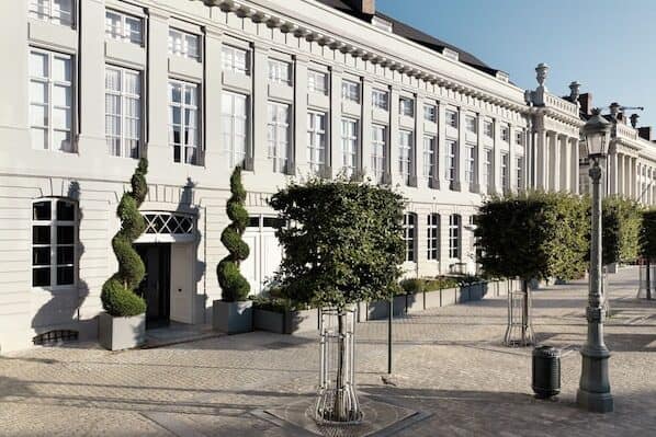 The facade of a white Brussels City Centre hotel surrounded by lamp post and bushes