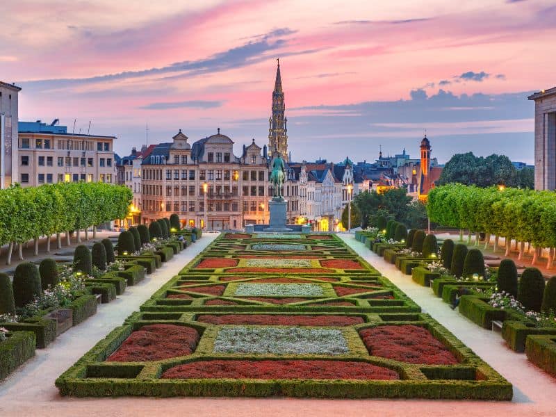 The town hall in Brussels during sunset with a pristine garden in front of it.