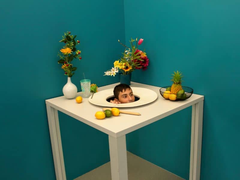Optical illusion where the had of a man is on the table being served as food.