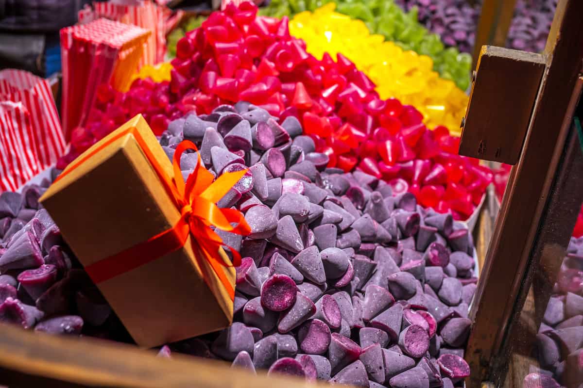 Red, yellow, green, purple cuberdons and a gift box inside a cart with clear glass partition.
