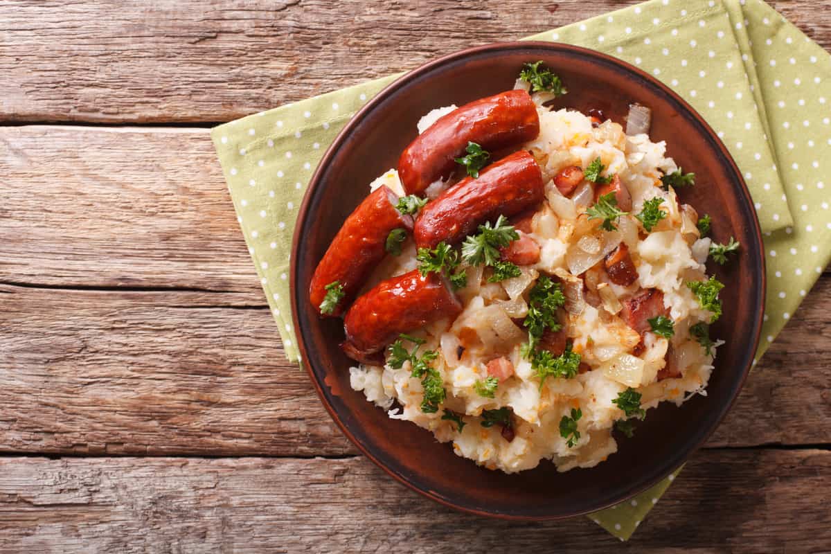 A Dutch winter meal: stamppot of potatoes, cabbage and carrots, with sausages close-up on a plate. horizontal view from above