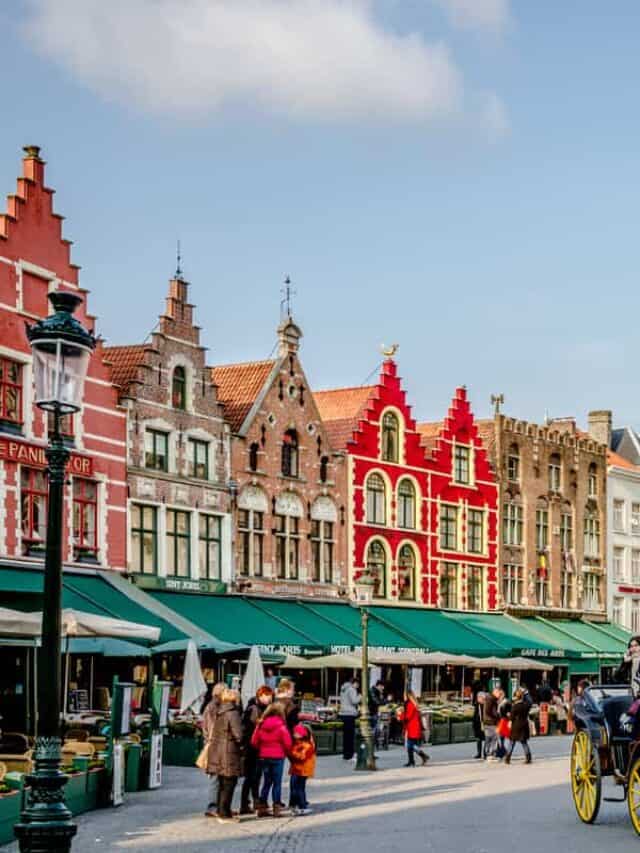 Colorful Buildings, flags, bicycles, stalls, and a horse Carriage at Grote Markt Square in Bruges.