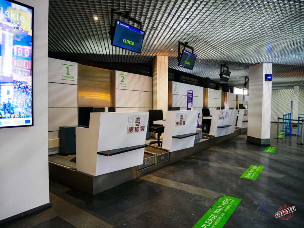 Four empty check-in counters with each hanging digital screen indicating that it is closed.