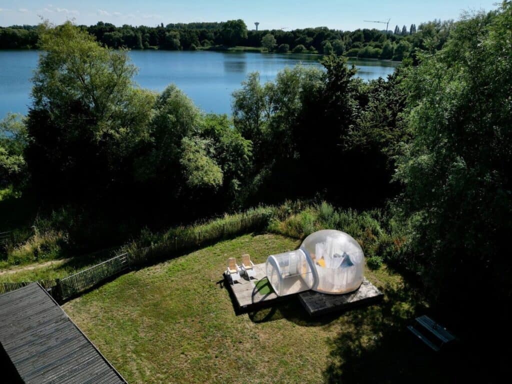 Aerial view of Glamping Universe showcasing various luxury tents and structures amidst a lush landscape with pathways weaving through greenery emphasizing the harmony between comfort and natural surroundings.