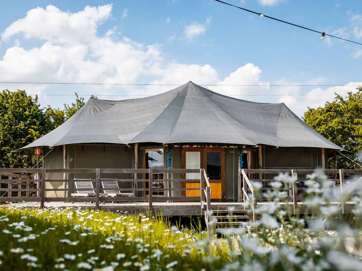 Exterior view of the Green Fields - Durbuy glamping site, depicting a tranquil, lush green meadow.