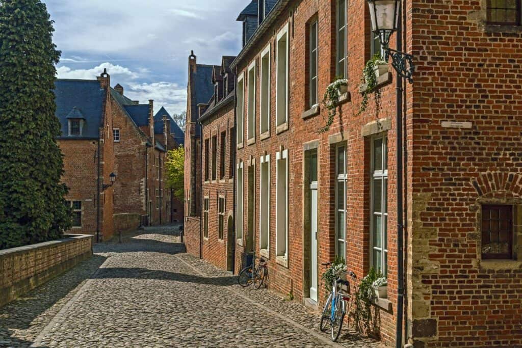 A small cobblestone street and old houses with a couple of bikes in the Grand Beguinage in Leuven.