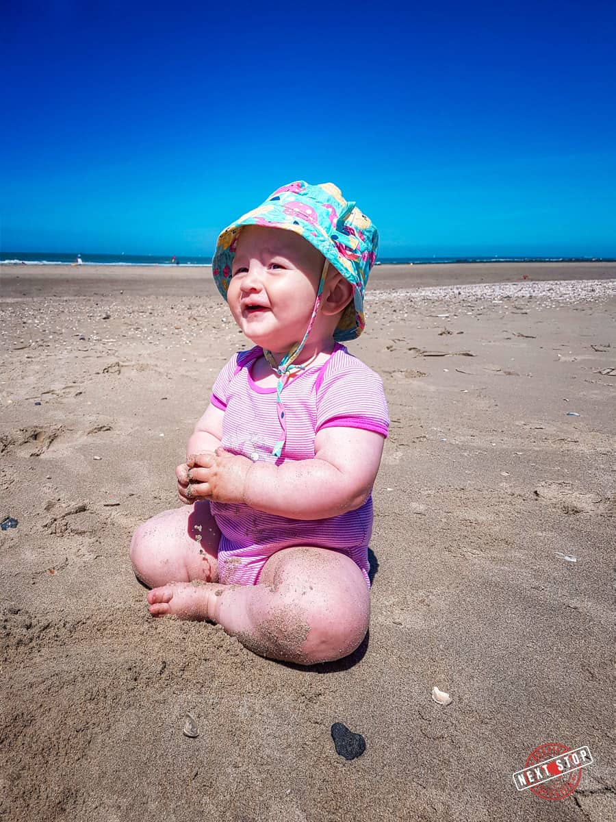 My 1 year old son on the beach with a blue hat.