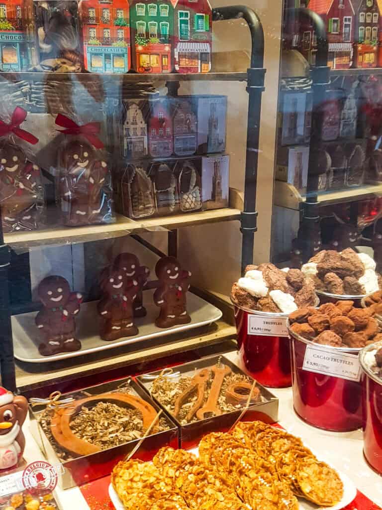 A chocolate shop in Bruges with various chocolate displays in front.