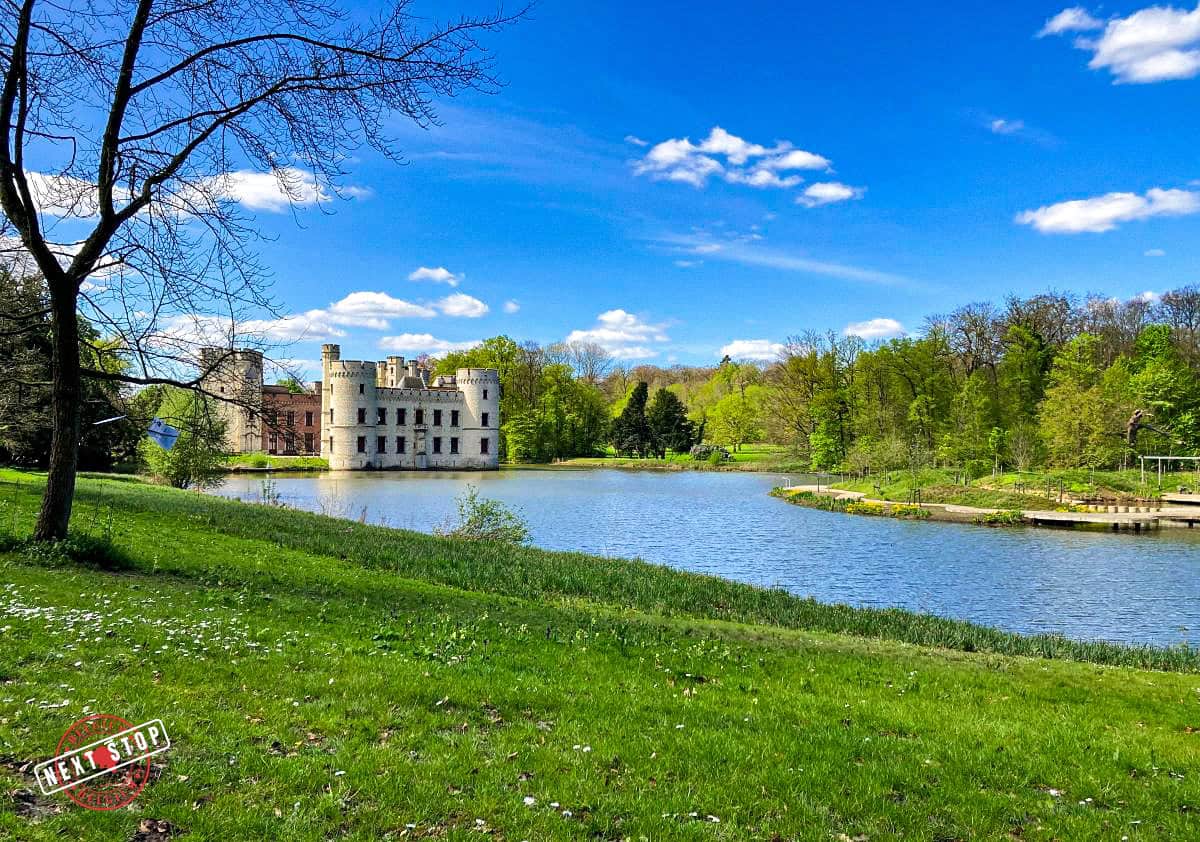 A green lawn beside a mini lake and you can also see a castle at the back.