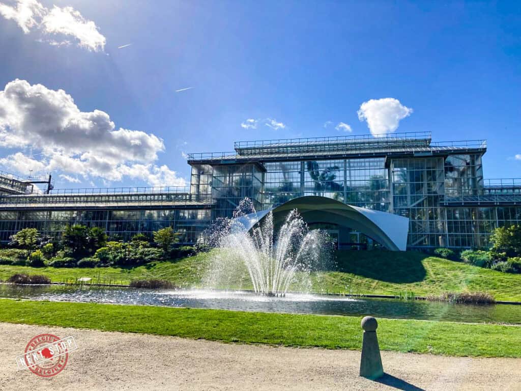 A glass building with a mini fountain in front of it.