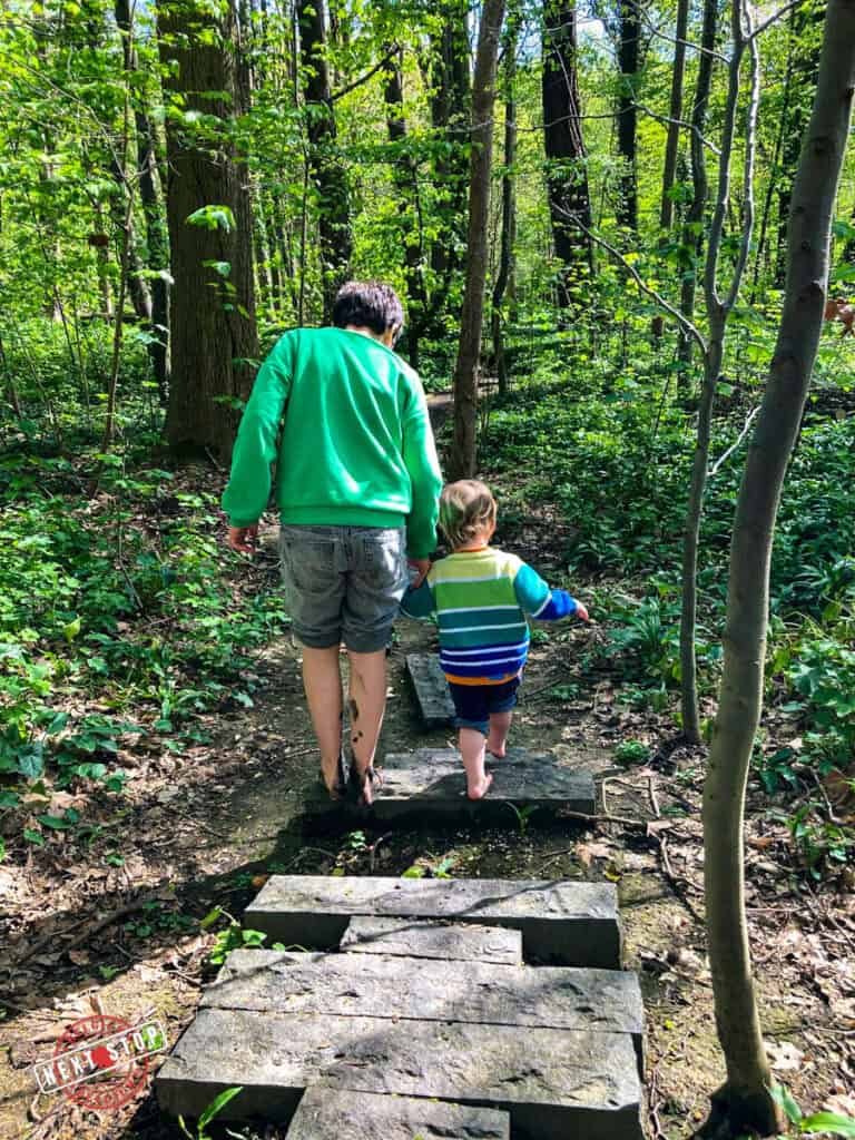 Walking barefoot with a kid at the stone path in the botanical garden.